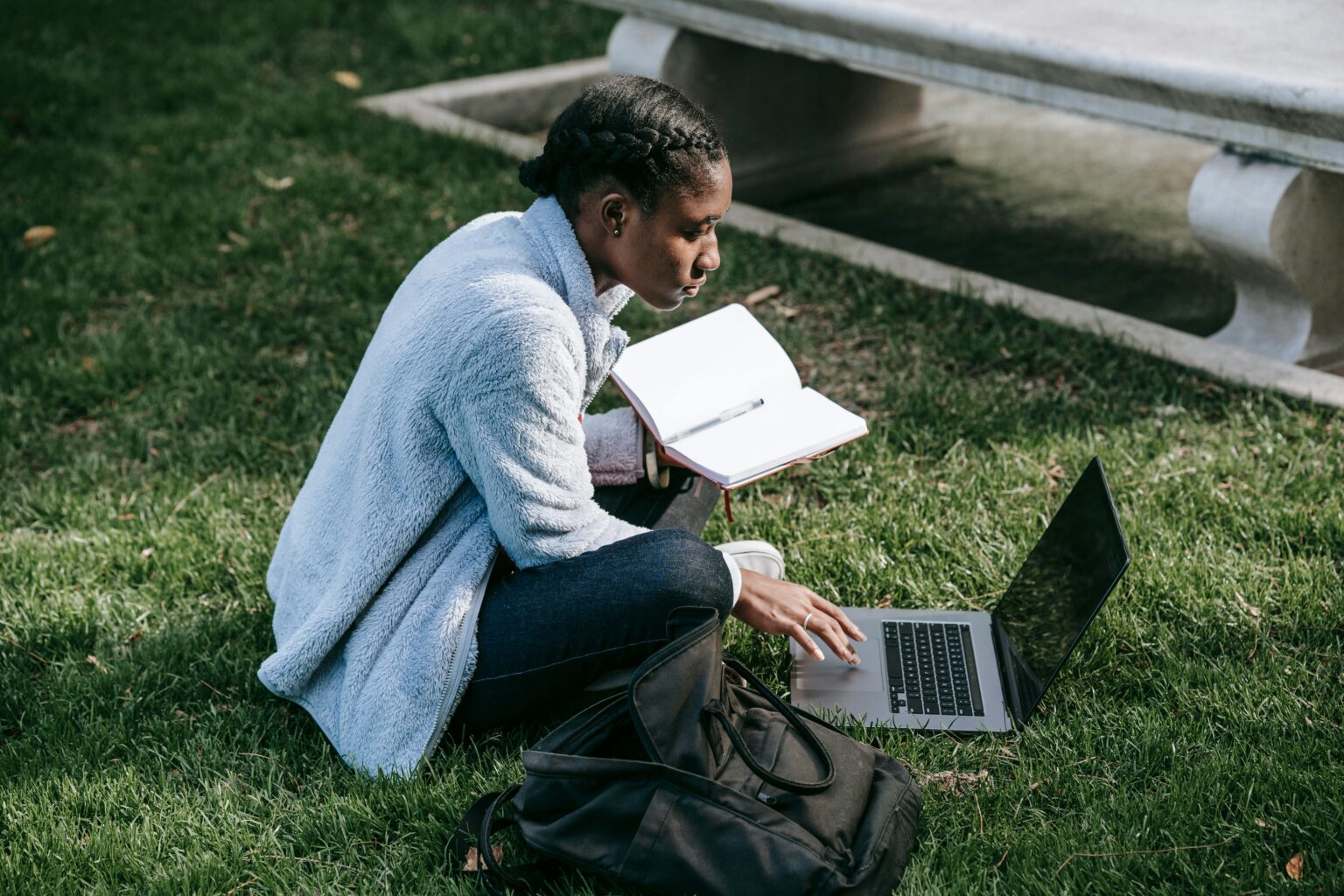 Ethnic student with laptop on lawn