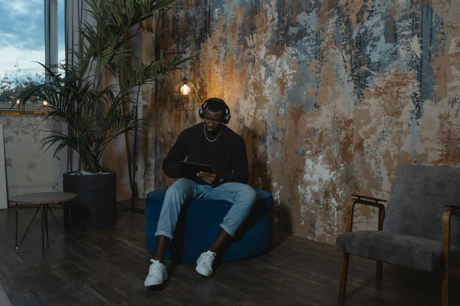 Man in Black Jacket and Blue Denim Jeans Sitting on Blue Sofa Chair