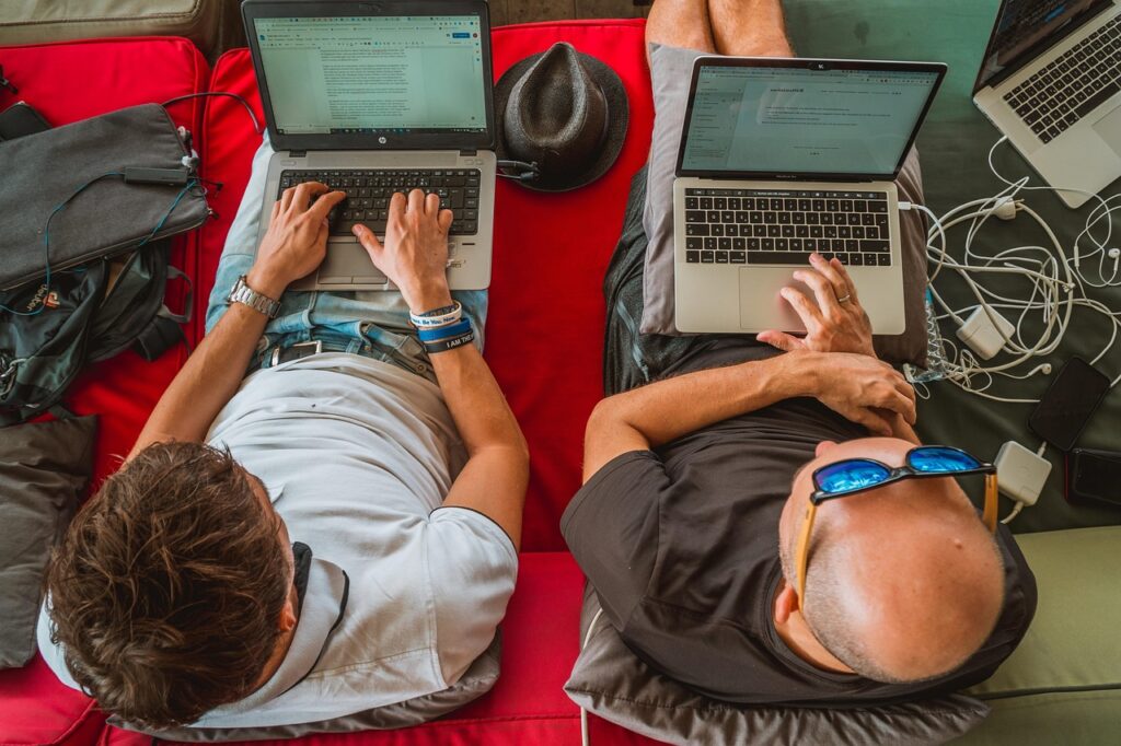 two men sitting and using laptops