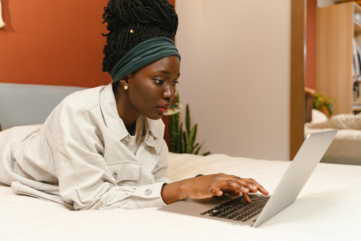 freelance skills in demand Caribbean Woman Lying on Bed Using Laptop